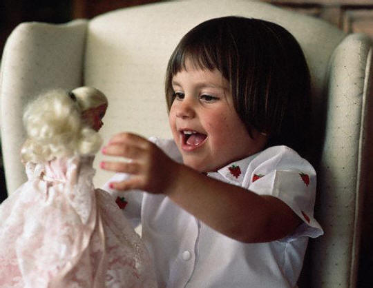 A young girl plays with a Barbie