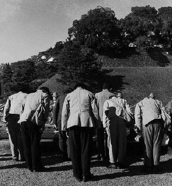 A group of men bow before the grounds and moats surrounding the Imperial Palace in Tokyo. 1946