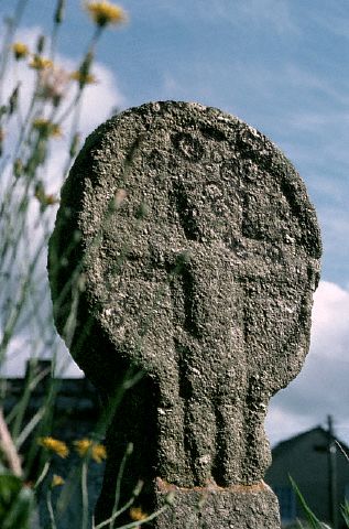 A stone celtic cross with a human figure forming the arms of the cross