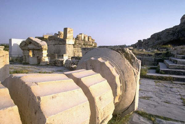 The fluted shaft and base of a fallen column lie among the ruins at Eleusis, Greece