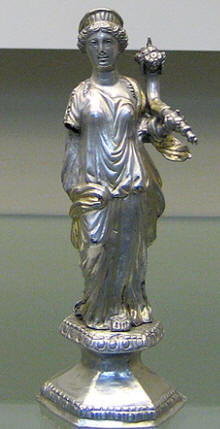 The crowned goddess holds a cornucopia in her left hand