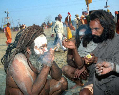 After the bath a naked sadhu has a go at 'hashish' or grass